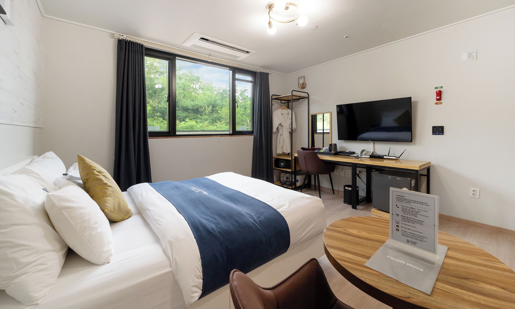 A hotel room with a bed, a desk, a chair, a television, and a window with curtains.
