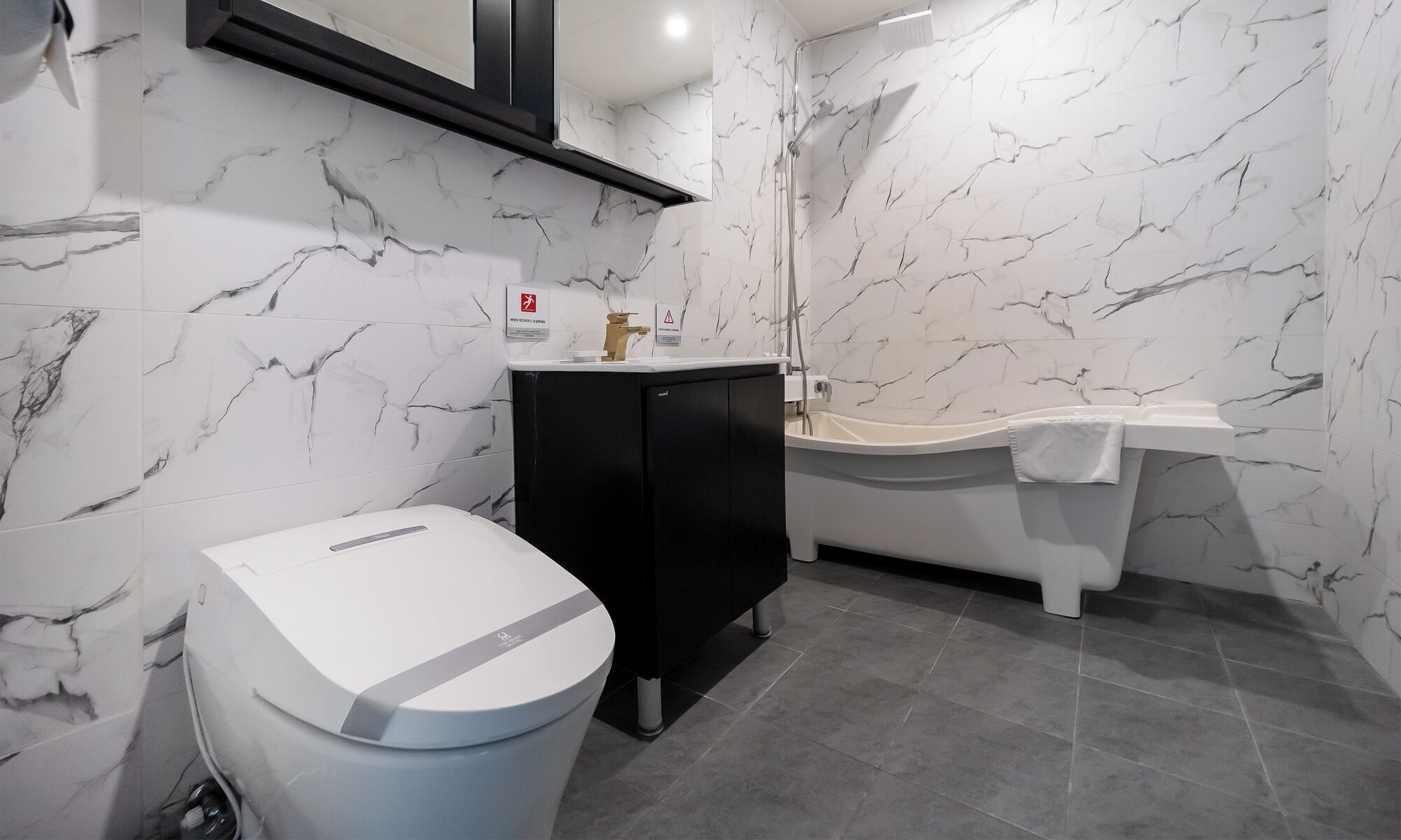 A modern bathroom with a toilet, black cabinet, and a bathtub with a white sink.