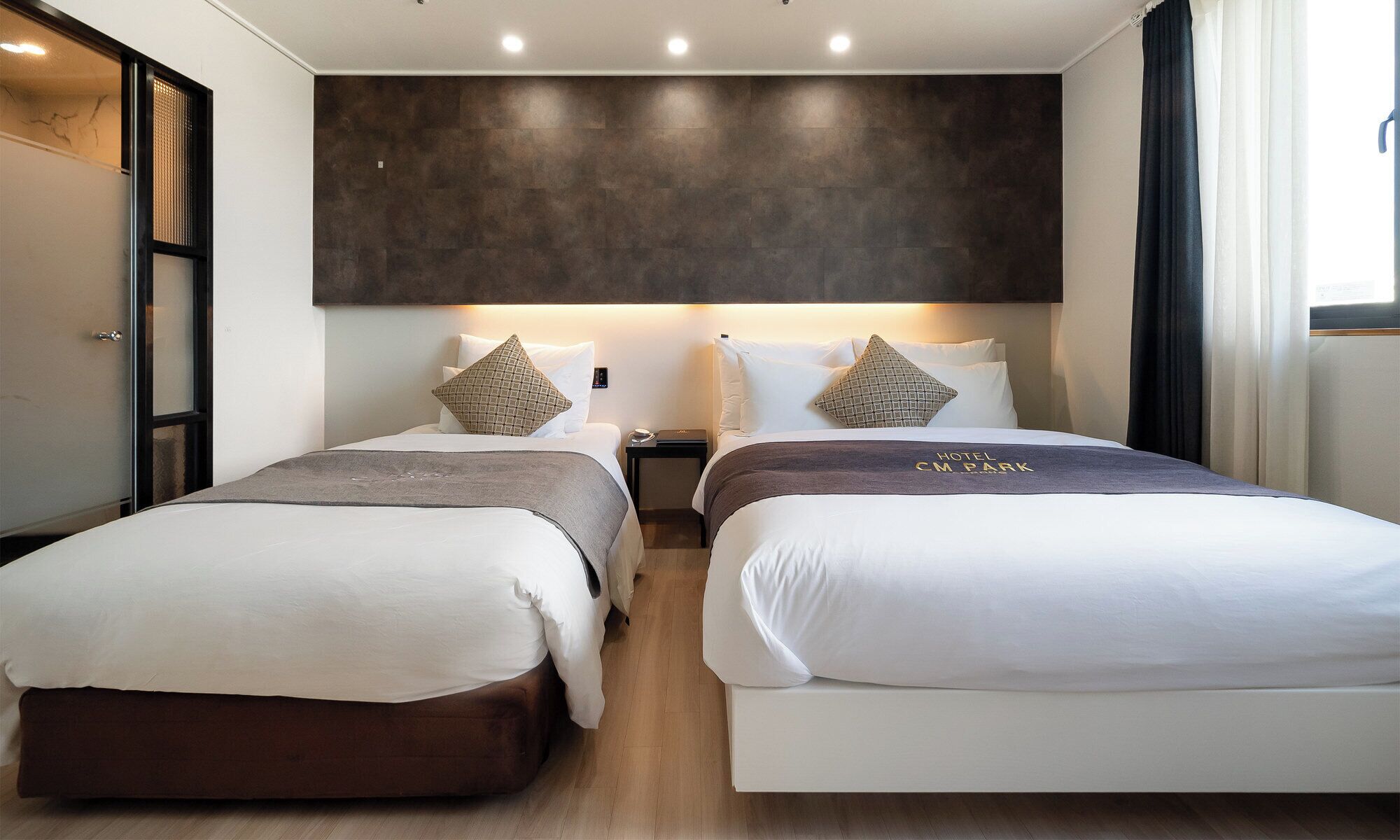 Habitación de hotel con dos camas, una pared de acento oscura y un diseño moderno.
