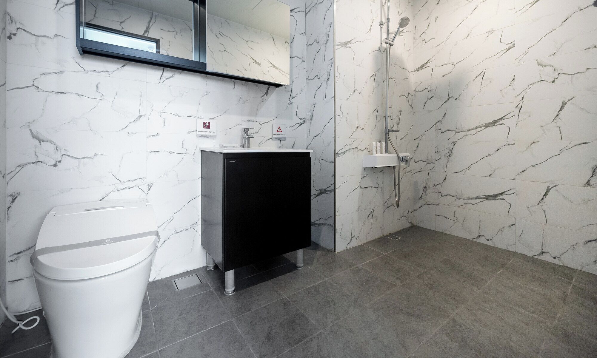 A modern bathroom with a white toilet, a black cabinet, and a shower area.