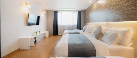 Una habitación de hotel moderna con dos camas, un televisor, un escritorio y un amplio ventanal con cortinas.