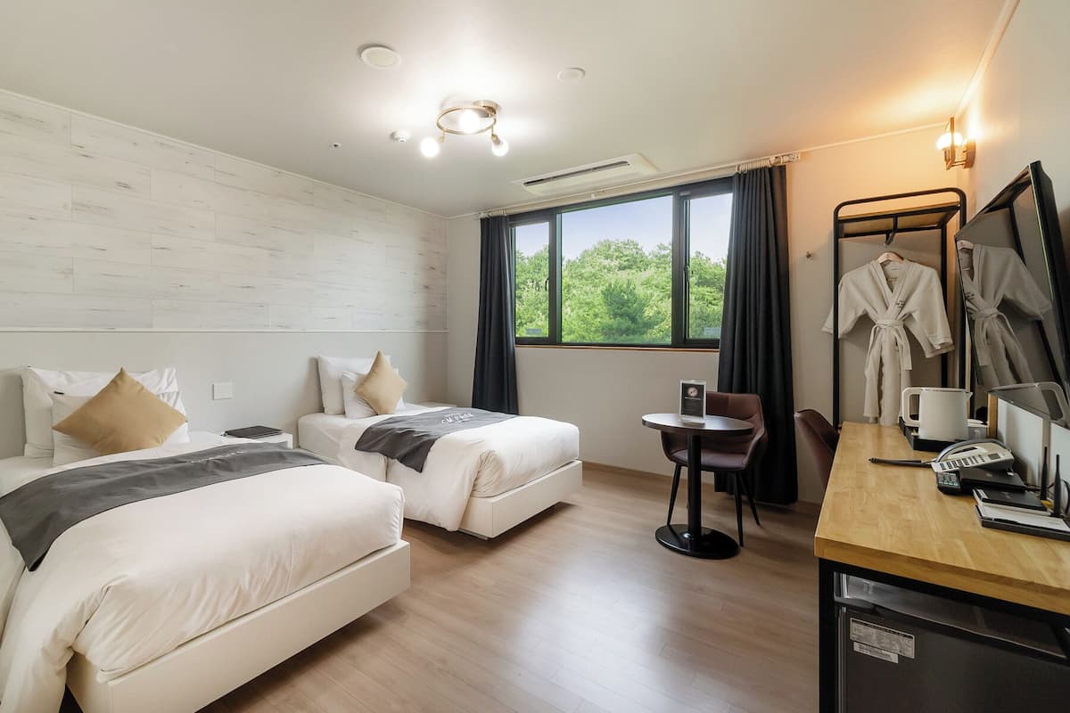 Una habitación de hotel con dos camas, un escritorio con teléfono, cafetera y espejo.
