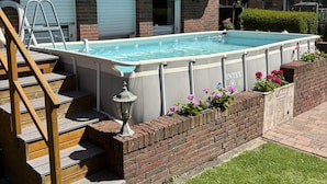 Ein Wohnhaus mit Swimmingpool, Backsteinfassade und einer Treppe zum Eingang.