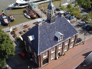 Edifici històric amb una torre del rellotge destacada, al costat d'un canal amb barques.