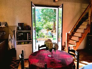 A dining area with a table set for two, a microwave, and a coffee maker on a shelf.
