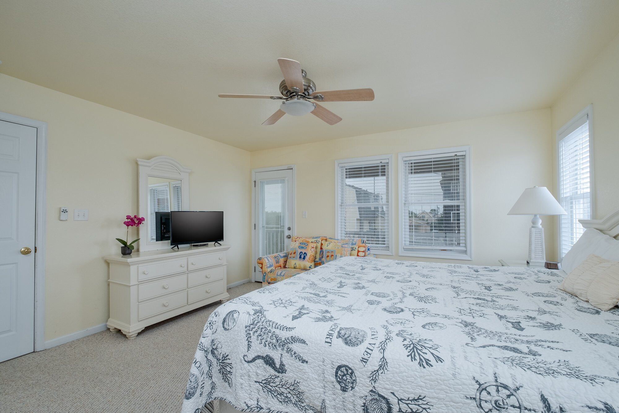 Ein Schlafzimmer mit Bett, Kommode, Fernseher und Deckenventilator.