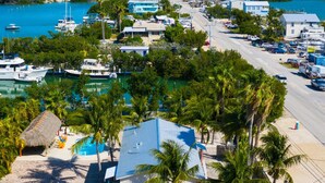 A coastal property with a swimming pool, palm trees, and a colorful fence. - Perfect 7-Night Keys Getaway: Pool, Tiki & Dock (Marathon)