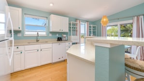 A modern kitchen with white cabinets, a wooden countertop, and a view of the outdoors. - Perfect 7-Night Keys Getaway: Pool, Tiki & Dock (Marathon)