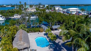 A resort with a swimming pool surrounded by palm trees and a thatched-roof hut. - Perfect 7-Night Keys Getaway: Pool, Tiki & Dock (Marathon)