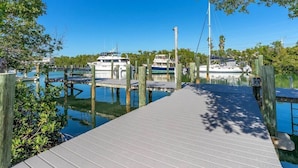 A wooden dock leading to a marina with several boats docked. - Perfect 7-Night Keys Getaway: Pool, Tiki & Dock (Marathon)