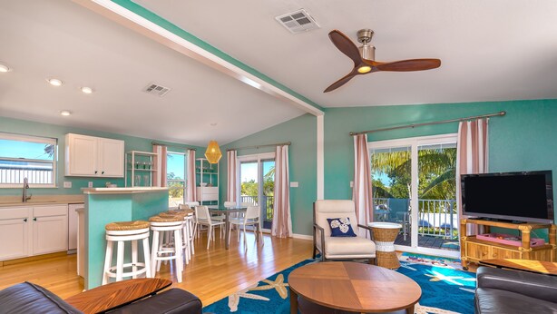 A spacious living area with a ceiling fan, a dining set, and a TV. - Perfect 7-Night Keys Getaway: Pool, Tiki & Dock (Marathon)