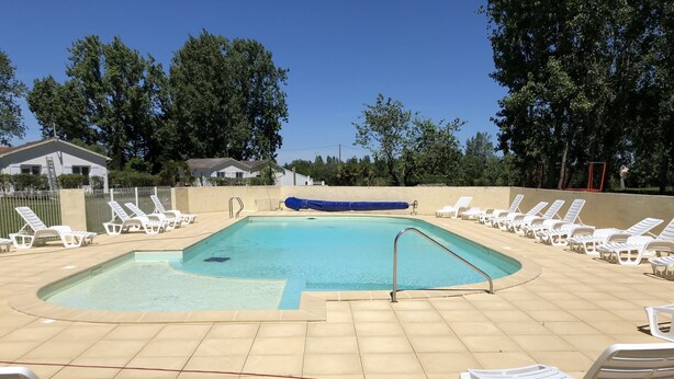 A swimming pool with white lounge chairs and a blue cover. - --Gite Les Courlis-- (Le Perrier)