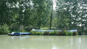 A calm river with a boat docked on the left. - --Gite Les Courlis-- (Le Perrier)