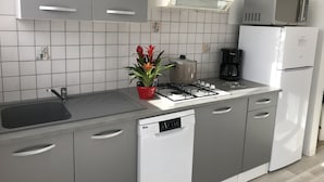 A modern kitchen with grey cabinets, a white dishwasher, a gas stove, a microwave, and a coffee maker. - --Gite Les Courlis-- (Le Perrier)