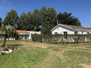 A white building with a tiled roof, surrounded by a well-maintained lawn and dense trees. - -Gite The Templars- (Le Perrier)