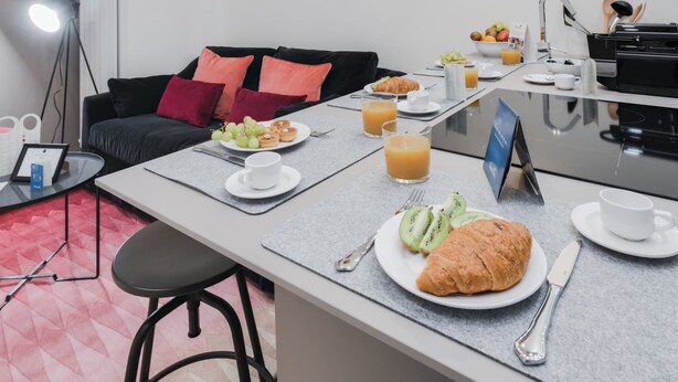Una mesa con un desayuno que incluye croissants, rodajas de kiwi y jugo de naranja.