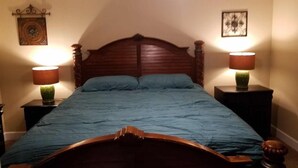 Une chambre à coucher avec un lit en bois, deux lampes de chevet et un ventilateur de plafond.
