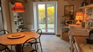 Een gezellige keuken met houten vloeren, een eettafel met stoelen, een magnetron en een spoelbak.