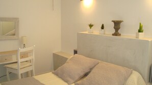 Een slaapkamer met een bed, een bureau, een stoel, een spiegel en wandlampen.