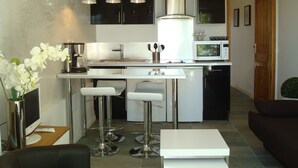 Een moderne keuken met een centraal eiland, barkrukken, een koffieapparaat en een magnetron.