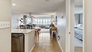 A spacious kitchen with a central island, a dining area with chairs, and a view of the ocean through large windows. - Oceanfront | Updated 2nd Floor Amelia Surf and Racquet Condo | Both Bedrooms Oceanfront (Fernandina Beach)