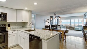 A modern kitchen with white cabinetry, a granite countertop, and stainless steel appliances. - Oceanfront | Updated 2nd Floor Amelia Surf and Racquet Condo | Both Bedrooms Oceanfront (Fernandina Beach)