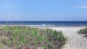 A beach with a clear sky, sandy shore, and tall grasses in the foreground. - Oceanfront | Updated 2nd Floor Amelia Surf and Racquet Condo | Both Bedrooms Oceanfront (Fernandina Beach)