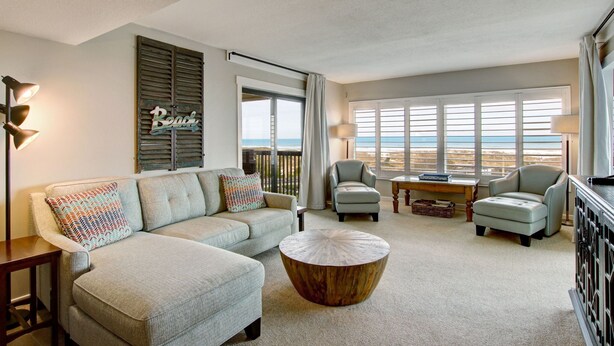 A spacious living room with a sofa, armchairs, a coffee table, and large windows offering a view of the beach. - Oceanfront | Updated 2nd Floor Amelia Surf and Racquet Condo | Both Bedrooms Oceanfront (Fernandina Beach)