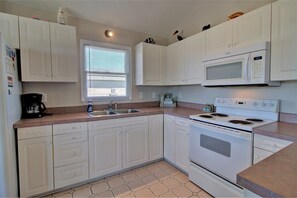 Kitchen features a central island, microwave, double sink, and coffee maker.