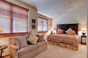 A bedroom with a bed, a sofa, and two bedside tables with lamps. - The Timbers Condo 2G - Mountain Views, Walk to Downtown & Pet Friendly (Ketchum)