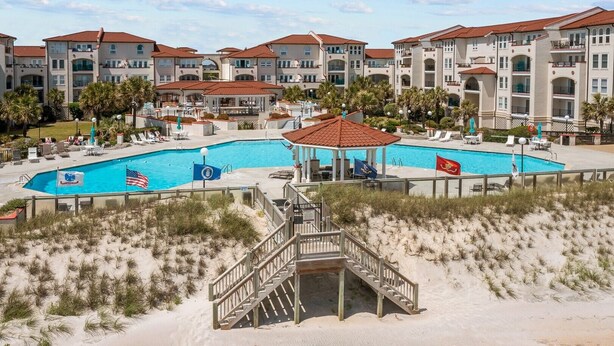 A resort with multiple swimming pools, a beach area, and a building with a red roof. - Oceanfront 2-bedroom condo at North Topsail Beach, perfect for family getaways. (North Topsail Beach)