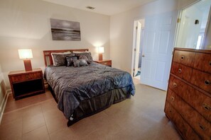 A bedroom with a bed, nightstands, a dresser, and a door. - Oceanfront 2-bedroom condo at North Topsail Beach, perfect for family getaways. (North Topsail Beach)