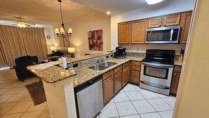A modern kitchen with granite countertops, stainless steel appliances, and wooden cabinets. - The Inn at Dauphin Island 104 Walk right out to Pools and Beach! (Dauphin Island)