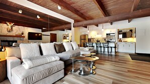 A spacious living area with a large sofa, a fireplace, and a kitchen with bar stools. - 🌲Timberline B1D Premier 2-Bedroom ~Hot Tub~Pool~WiFi~Ski-in/out~Local Shuttle🌲 (Snowmass Village)