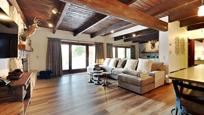 A spacious living room with a wooden ceiling, a large sofa, a dining table, and a fireplace. - 🌲Timberline B1D Premier 2-Bedroom ~Hot Tub~Pool~WiFi~Ski-in/out~Local Shuttle🌲 (Snowmass Village)