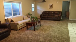 A living room with a beige sofa, a brown leather couch, a coffee table with a plant, and a fireplace.