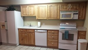 A kitchen with wooden cabinets, a white refrigerator, a microwave, a dishwasher, and a stove.