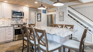 A modern kitchen with granite countertops, stainless steel appliances, and a central island with bar stools. - Sun Valley Village | Pool Access | Deck (Sun Valley)