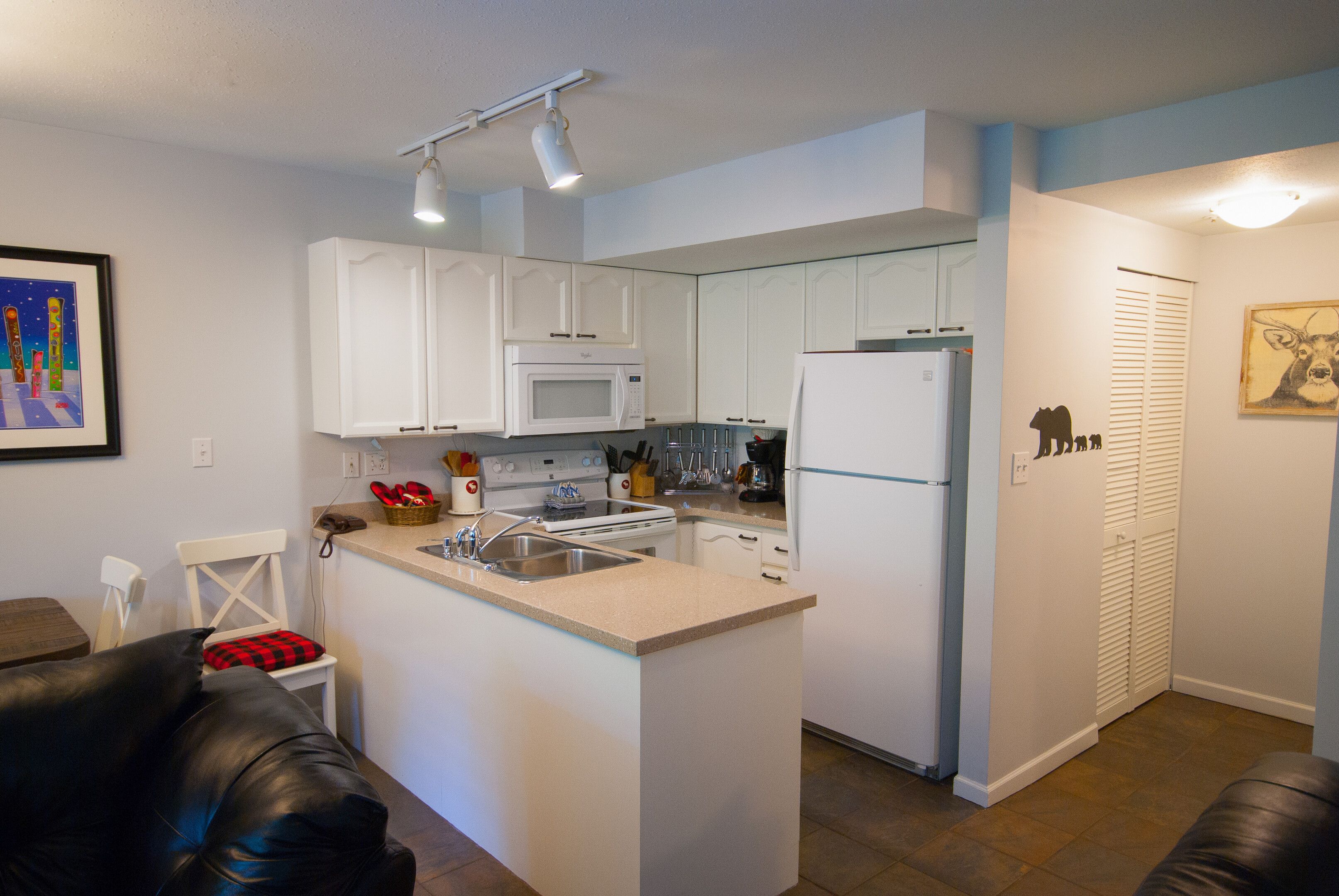 A compact kitchen with white cabinets, a microwave, a stove, and a refrigerator.