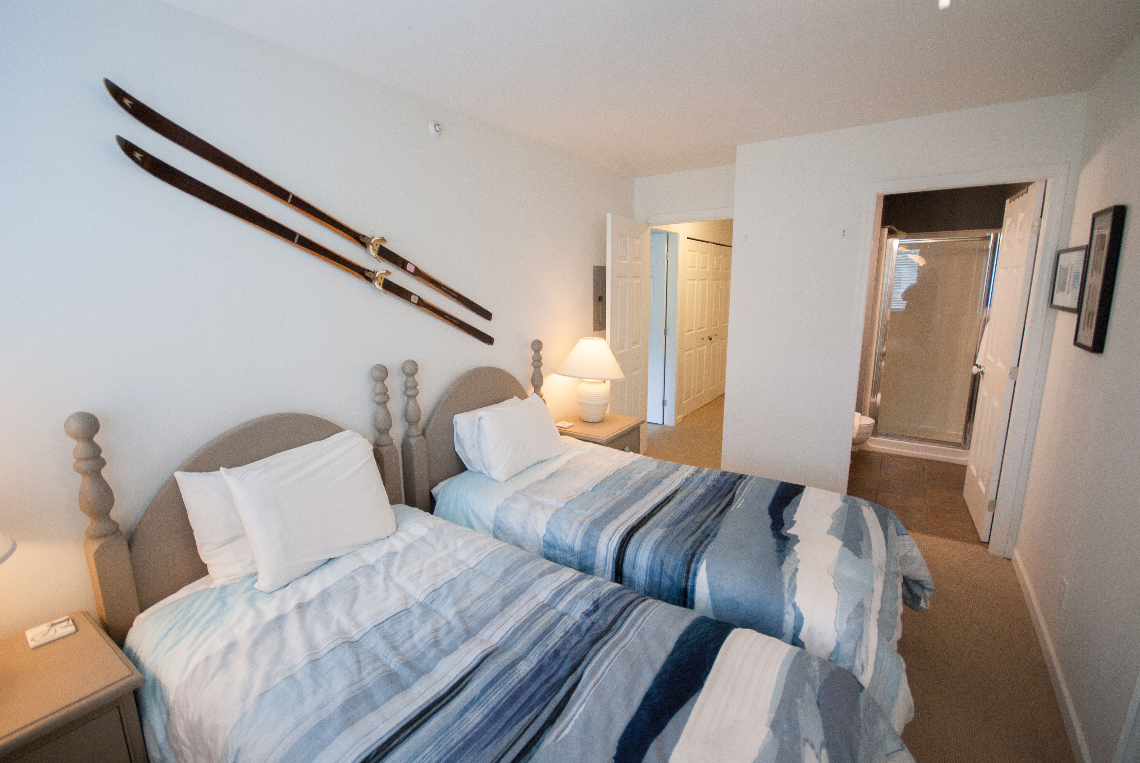 Une chambre avec deux lits, une table de chevet, une lampe et une paire de skis accrochés au mur.