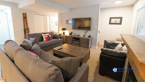 A modern living room with a sofa, coffee table, and a TV mounted on the wall.