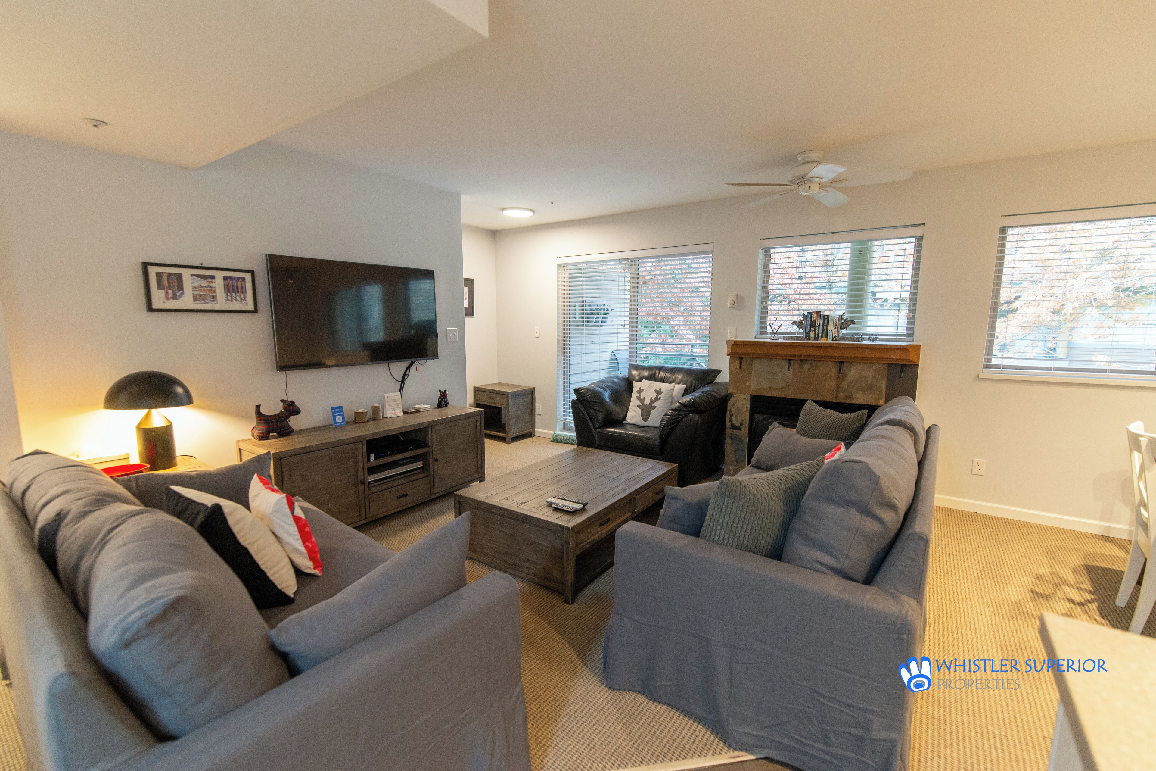 A modern living room with a flat-screen TV, grey sofas, a coffee table, and a fireplace.
