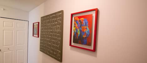Ein Flur mit drei gerahmten Kunstwerken an der Wand, einer weißen Tür und einem Teppichboden.