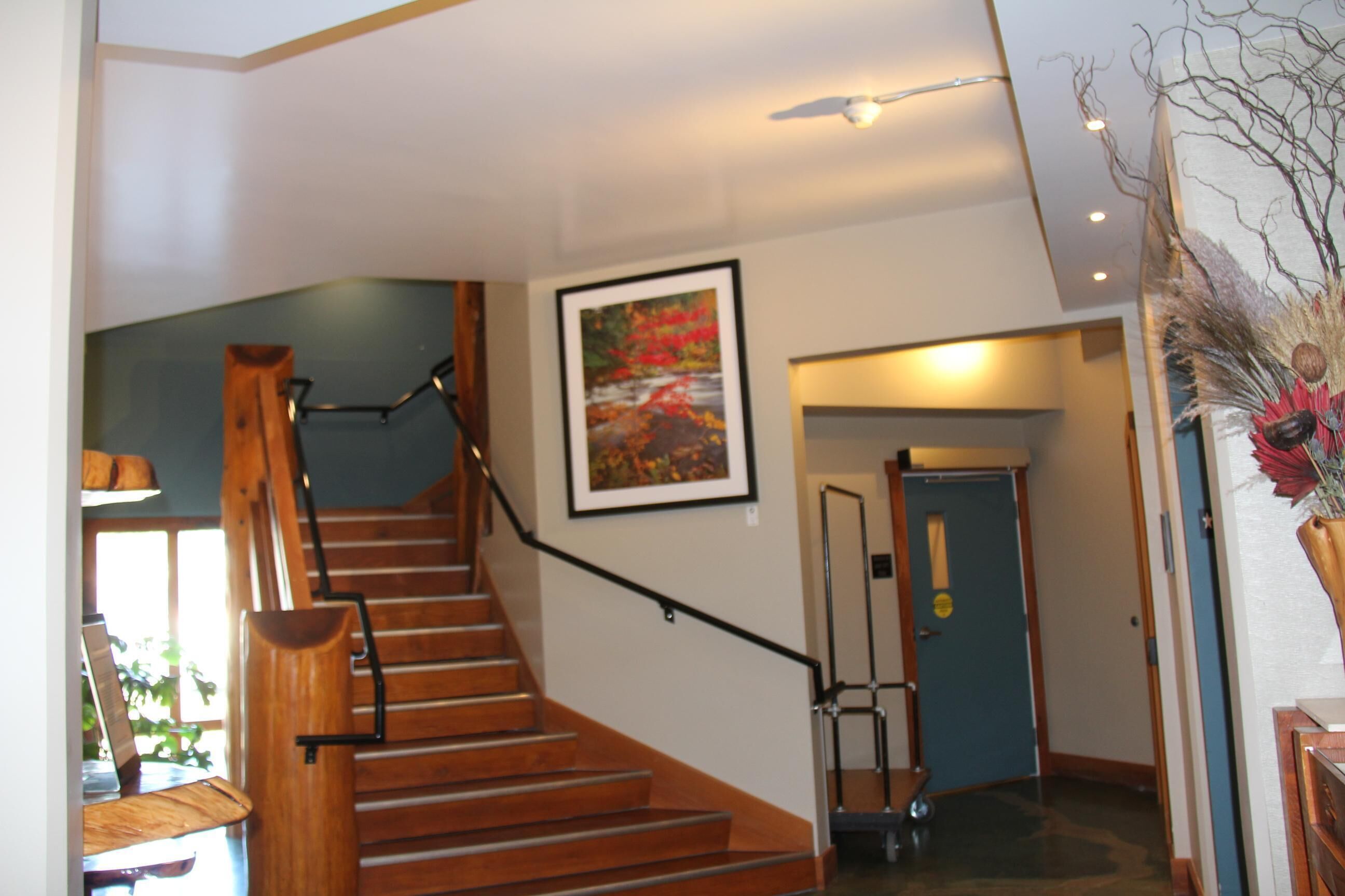 Eine Holztreppe mit Handlauf, ein gerahmtes Bild an der Wand und eine Tür im Hintergrund.