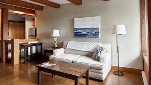A modern living room with a wooden ceiling, a white sofa, a coffee table, a lamp, and a painting on the wall. - Beautiful Condo in a Great Location, Oceanfront Complex - OE (Ucluelet)