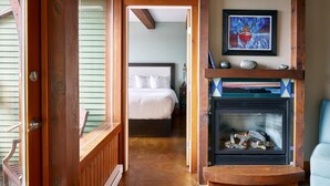 A cozy room with a wooden fireplace, a bed, and a painting on the wall. - Beautiful Condo in a Great Location, Oceanfront Complex - OE (Ucluelet)