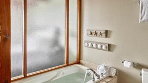 A bathroom with a bathtub, a window with a wooden frame, a towel rack, and a toilet. - Beautiful Condo in a Great Location, Oceanfront Complex - OE (Ucluelet)