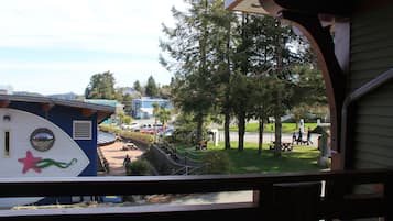 A view from a balcony overlooking a park with picnic tables, a playground, and a large tree.