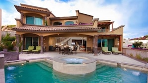 A multi-story resort with a swimming pool, outdoor seating, and a covered patio area.