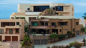 A multi-story building with a pool, outdoor seating, and a view of the ocean.